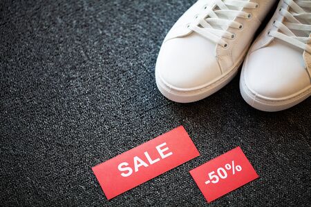 Pair of new stylish white sneakers with discount on gray background.の写真素材