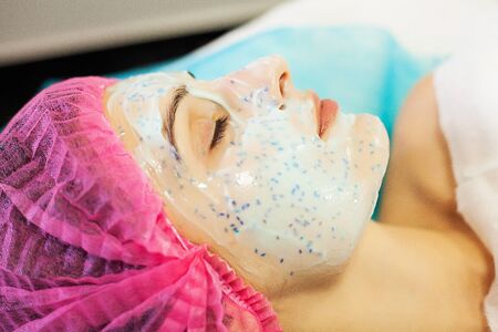 Spa therapy for young woman having facial mask at beauty salon.