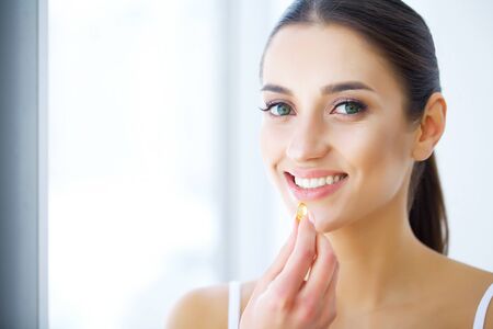 Beautiful Woman Holding Fish Oil Pill In Hand. Healthy Nutritionの写真素材