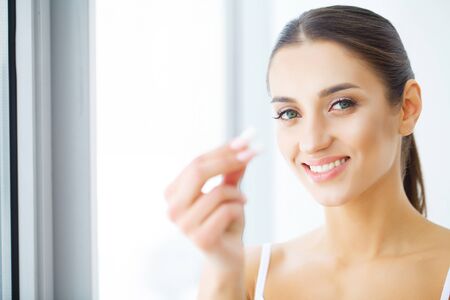 Dental care. Beautiful young woman eating chewing gum, smiling.の写真素材