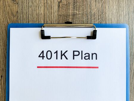 Paper with 401k plan on wood table.