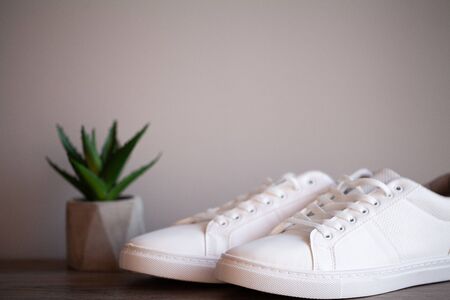 Pair of new stylish white sneakers on floor at homeの写真素材