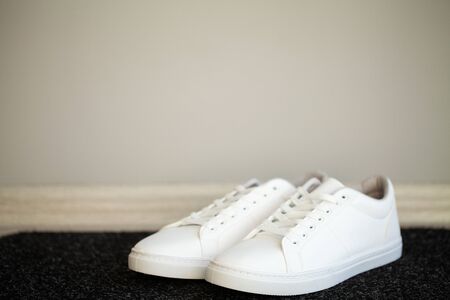 Pair of new stylish white sneakers on floor at homeの写真素材