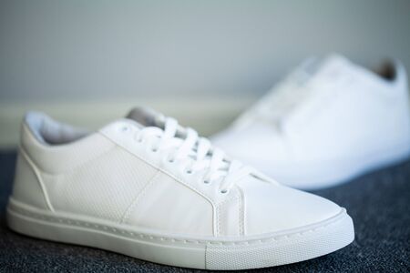 Pair of new stylish white sneakers on floor at homeの写真素材
