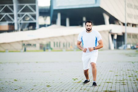 Fitness. Young man running in urban environmentの写真素材