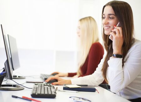 Two beautiful girls work in the office of a consulting company