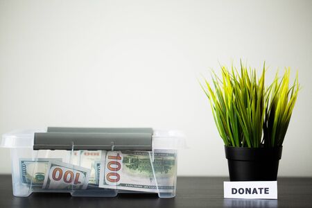 Donate box with dollars on wood deskの写真素材