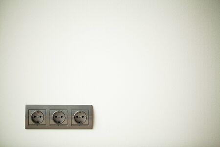Closeup view of a group of gray european electrical outlets located on a gray wallの写真素材