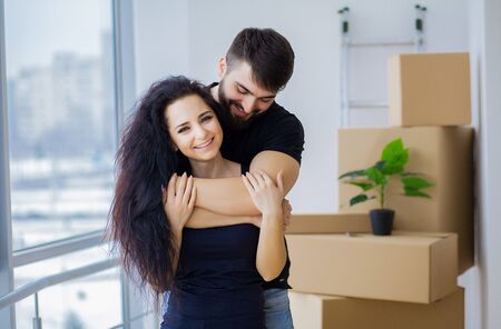 Couple showing keys to new home hugging looking at camera