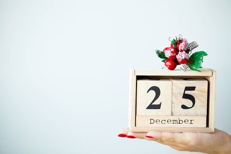 Woman in hand holds Christmas decorations on light background