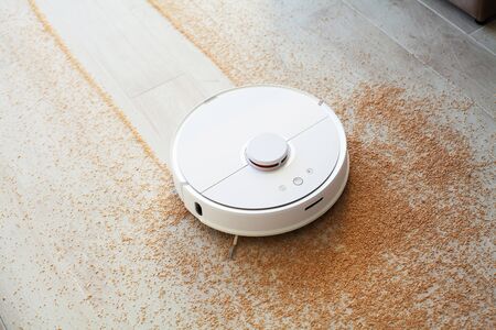 Smart House. Vacuum cleaner robot runs on wood floor in a living room