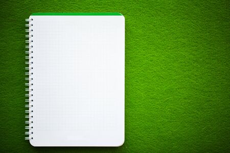 White notebook top view on green table.