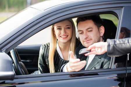 Happy couple buy new modern black car