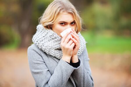 Woman portrait outdoor sneezing because cold and fluの写真素材
