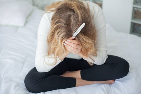 Worried sad woman Looking at a Pregnancy Test after resultの写真素材