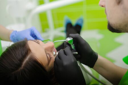 Dentist are treating teeth to client in dental office