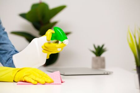 Young woman in gloves cleaning office tableの写真素材