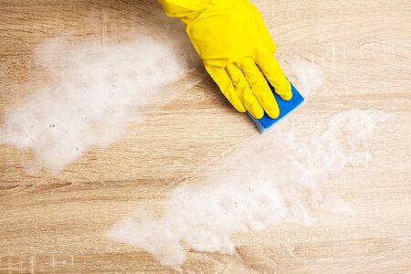 Employee using sponge for cleaning wood table.