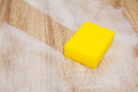 Employee using sponge for cleaning wood table.