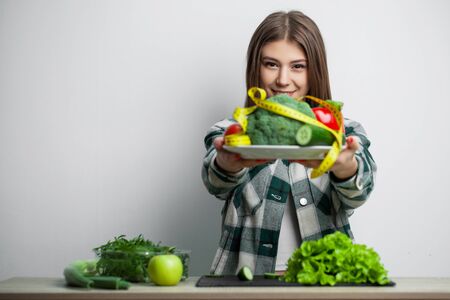 Young pretty woman adheres to diet and holds a plate of vegetablesの写真素材