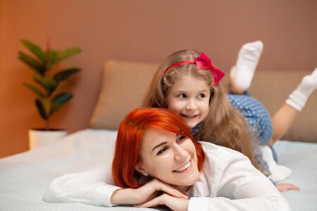 Mother and her baby daughter girl on bed in bedroom.の写真素材