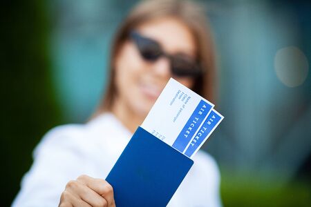 Woman holds plane tickets near airport in passport.の写真素材