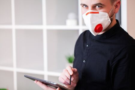 Man working in the office wearing a mask for protection from coronavirusの写真素材