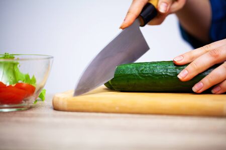 Concept of healthy eating, woman cuts fresh vegetables for salad.の写真素材