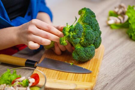 Concept of healthy eating, woman cuts fresh vegetables for saladの写真素材