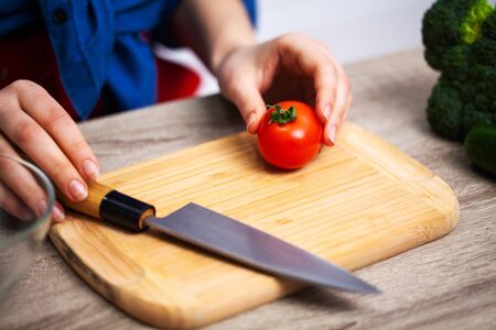 Concept of healthy eating, woman cuts fresh vegetables for salad
