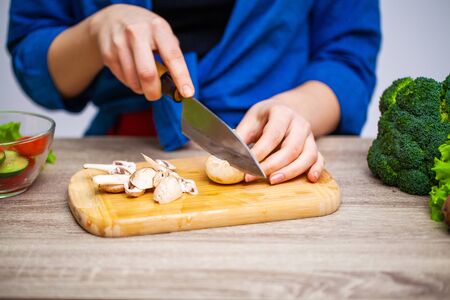 Concept of healthy eating, woman cuts fresh vegetables for saladの写真素材