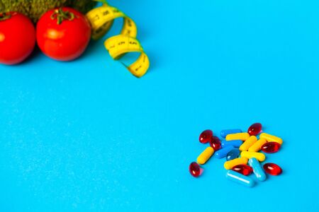 Pills for weight loss and tape measure on a blue background