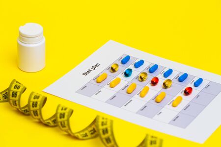 Diet plan and weight loss pills on a yellow background.の写真素材