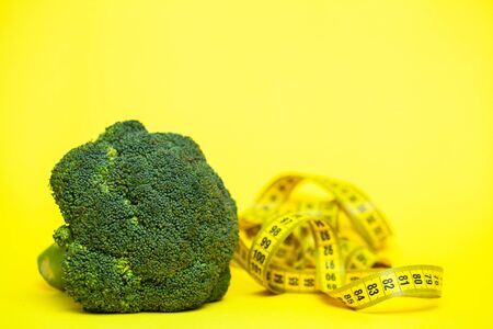Concept of weight loss, broccoli with tape measure on a yellow background.の写真素材