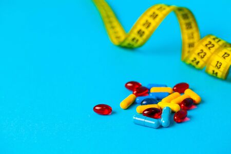 Pills for weight loss and tape measure on a blue backgroundの写真素材