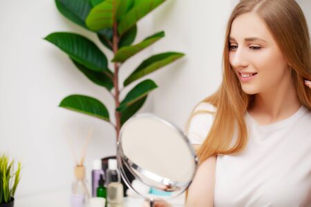 Pretty young female looking in the mirror after a showerの写真素材