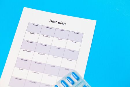 Diet plan and weight loss pills on blue background.