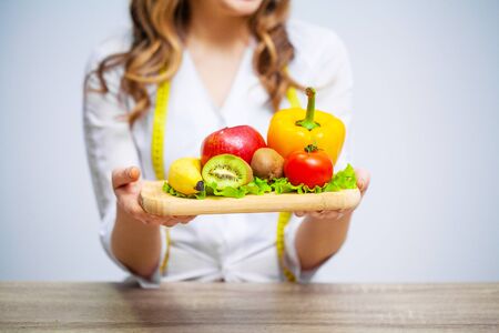 Nutritionist holding fresh fruits and vegetables for healthy diet.の写真素材