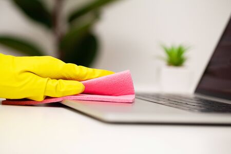 Close up of worker hand wiping dust in office in yellow gloves.の写真素材