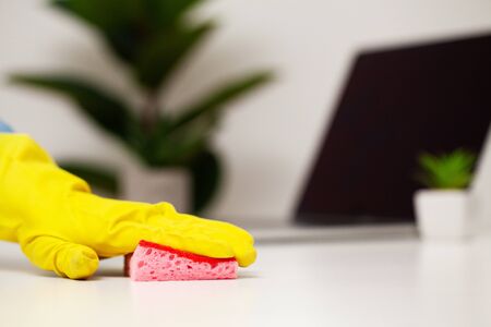Close up of worker hand wiping dust in office in yellow gloves.の写真素材