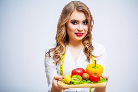The concept of healthy eating and diet girl holding vegetables on background white wallの写真素材