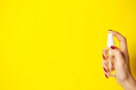 A woman uses antiseptic on yellow background