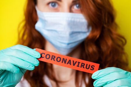 Woman in protective gloves holding inscription coronavirusの写真素材