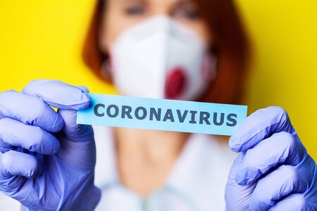 Woman in protective gloves holding inscription coronavirusの写真素材