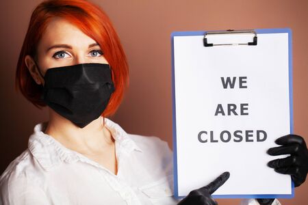 Woman holding blank with inscription we are closed calling for stop spreading covid-19.の写真素材