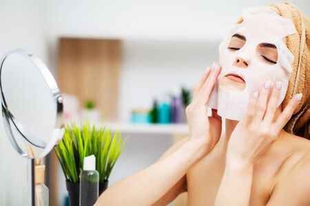 Woman in the bathroom applies cosmetics to skin careの写真素材