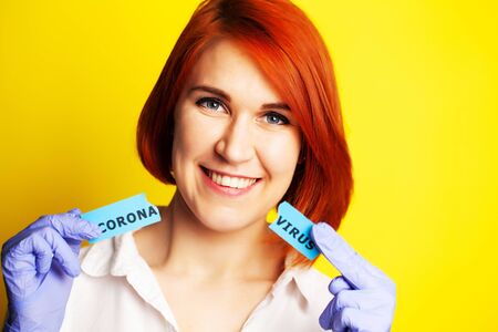 Woman in protective gloves holding inscription coronavirus