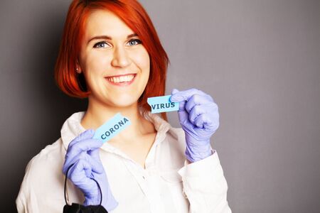 Woman in protective gloves holding inscription coronavirusの写真素材