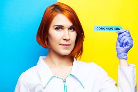 Woman in protective gloves holding inscription coronavirus