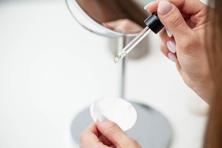 Close up woman puts a cream for face on hand
